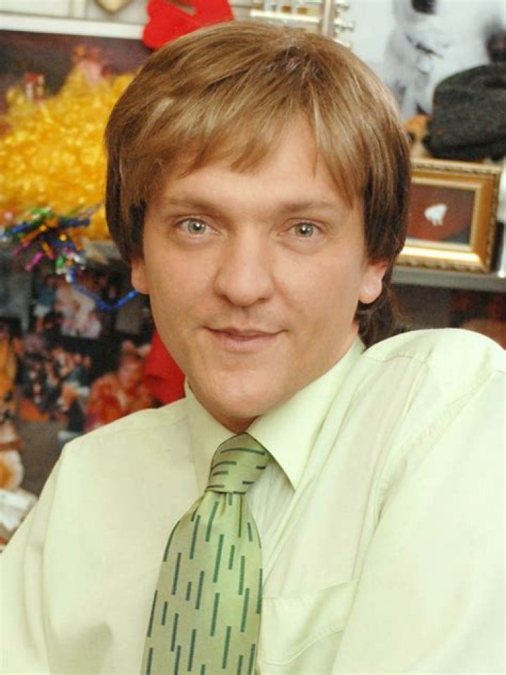 Chris Lilley in a blonde wig and surrounded by stuffed animals in Lunatics