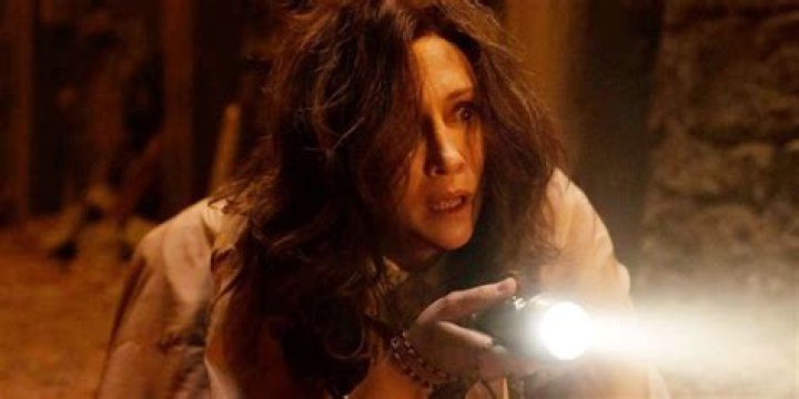 Loraine flashes a light while on her knees and looking scared in THe Conjuring The Devil Made Me Do It