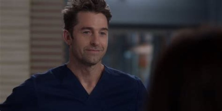 Nick smiling at the hospital in his scrubs on Grey's Anatomy