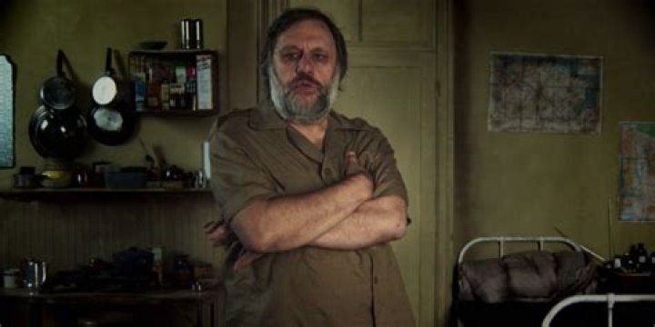 Zizek crossing his arms and standing in a room in The Pervert's Guide To Ideology.
